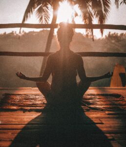 A woman meditating beneath a palm.