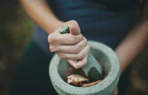 A person grinding herbs in a mortar and pestle.