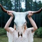 A witch holding up an animal skull