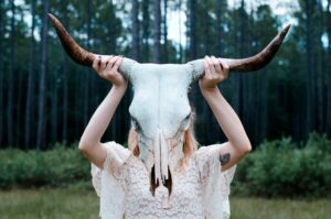 A witch holding up an animal skull