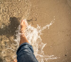 A person walking barefoot on the beach.