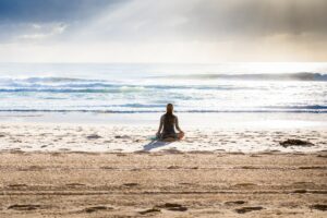 A woman meditating on the beach